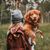 Toller on the arm, medium red dog breed with white spots, wet dog, dog you can carry but is not a small dog, dog similar to Kooiker, red dog breed, light brown dog