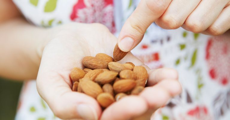 Close up of woman eating handful of almonds