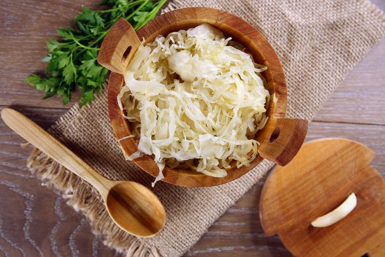 Sauerkraut in a wooden barrel Sauerkraut in einem Holzfass auf braunem Tisch
