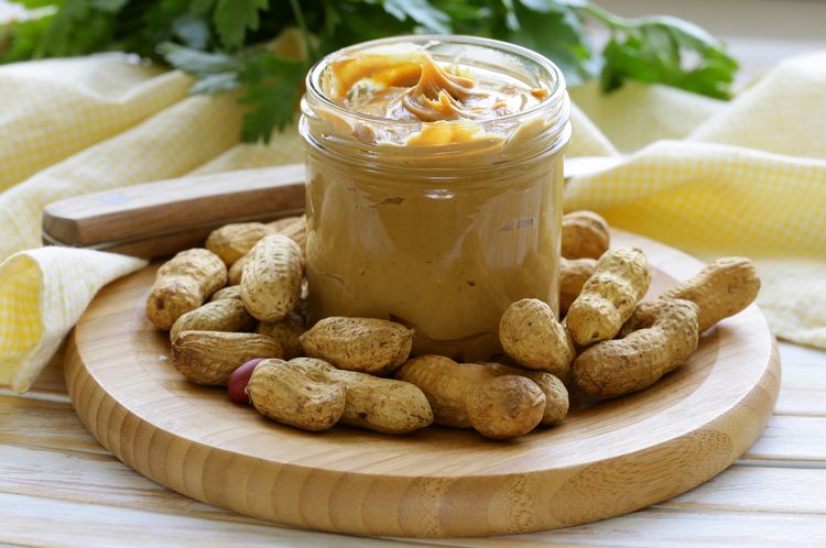 Mantequilla de cacahuete casera con nueces enteras sobre una mesa de madera